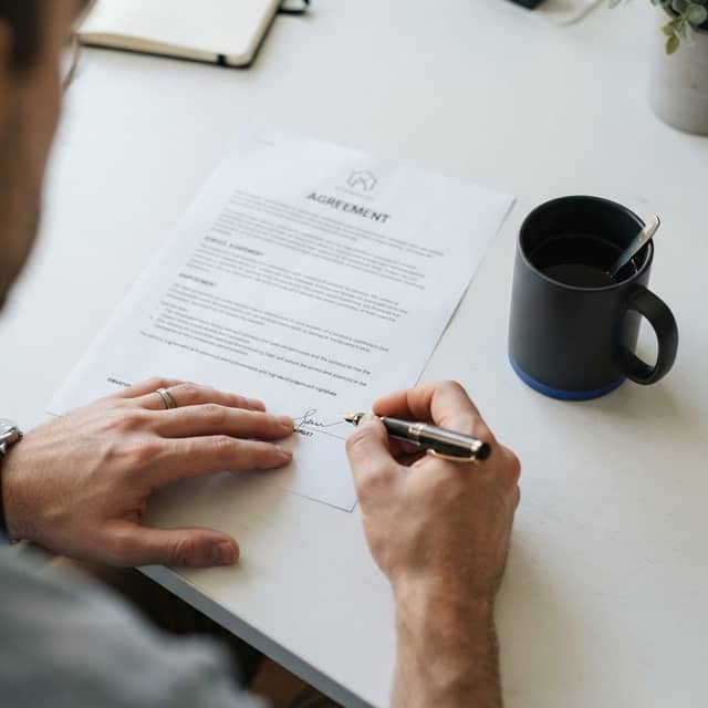 Close up of a hand signing a professional contract on a clean desk