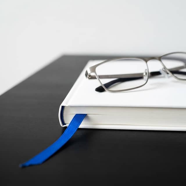 Glasses on a notebook with an electric blue bookmark