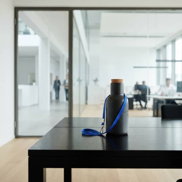 Ceramic carafe on a dark desk with a blue lanyard