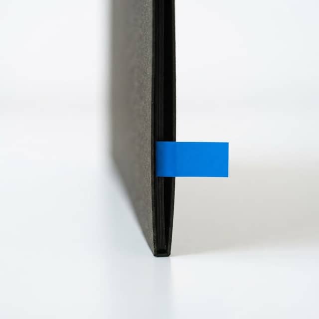 A close up of a black folder edge with a blue index tab.