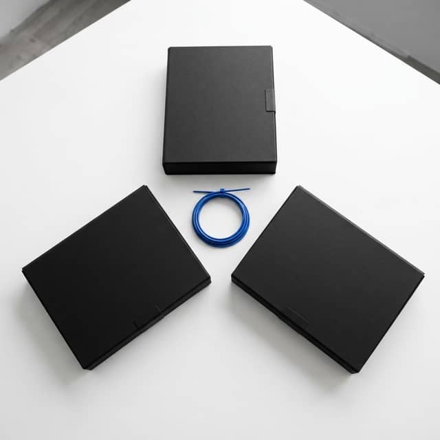 Three near black document cases arranged with a single blue cable tie on a white surface