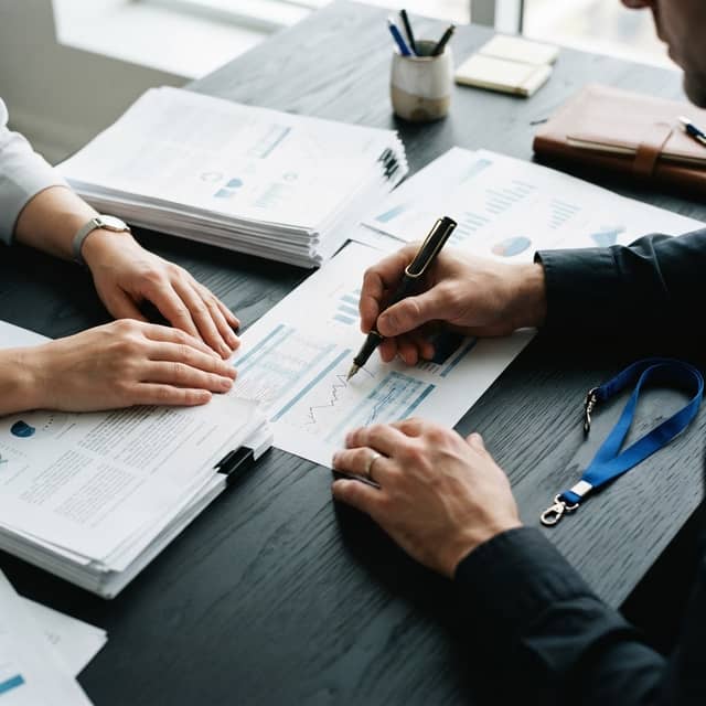 Professional hands reviewing physical business reports on a dark desk